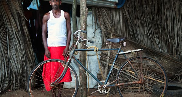 Man stood outside Shanti in Goa next to rusty old bike