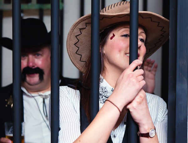 women dressed as cowgirl in fake jail house at party