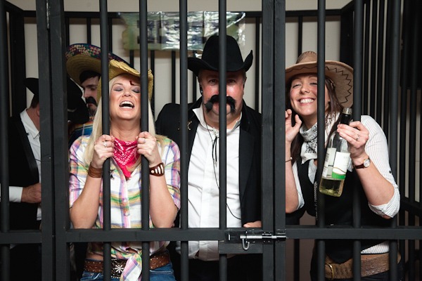 women dressed as cowgirl in fake jail house at party