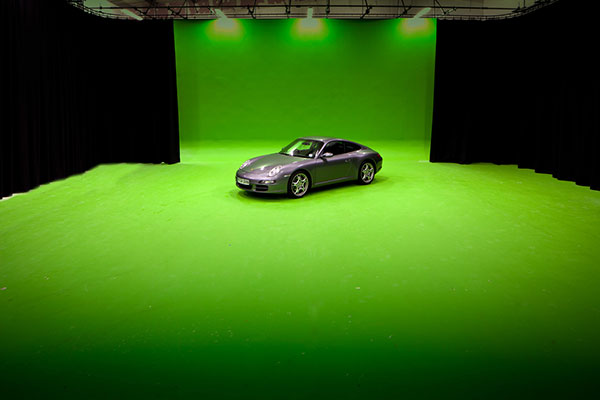 Large green screen studio with Porsche car in centre to give it a sense of scale