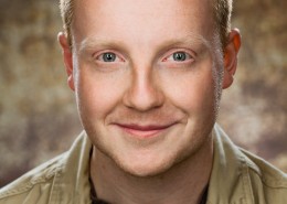 Actor headshot on brown speckled background featuring male with red hair