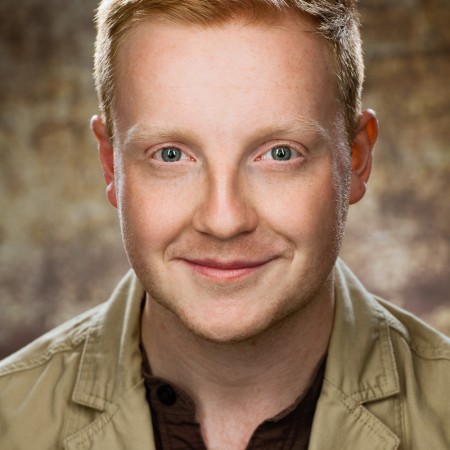 Actor headshot on brown speckled background featuring male with red hair