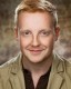 Actor headshot on brown speckled background featuring male with red hair