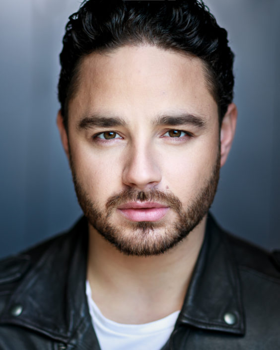 actor headshot portrait featuring Adam Thomas with beard taken outside against grey background
