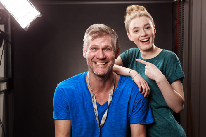 Behind scenes group shot features actor Amy-James Kelly and Colin Boulter in the studio after a shoot. photographed against a black background with studio light in shot