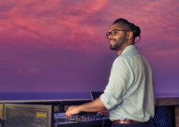 DJ playing a set on the decks of Explora one at twilight. Beautiful sky behind him