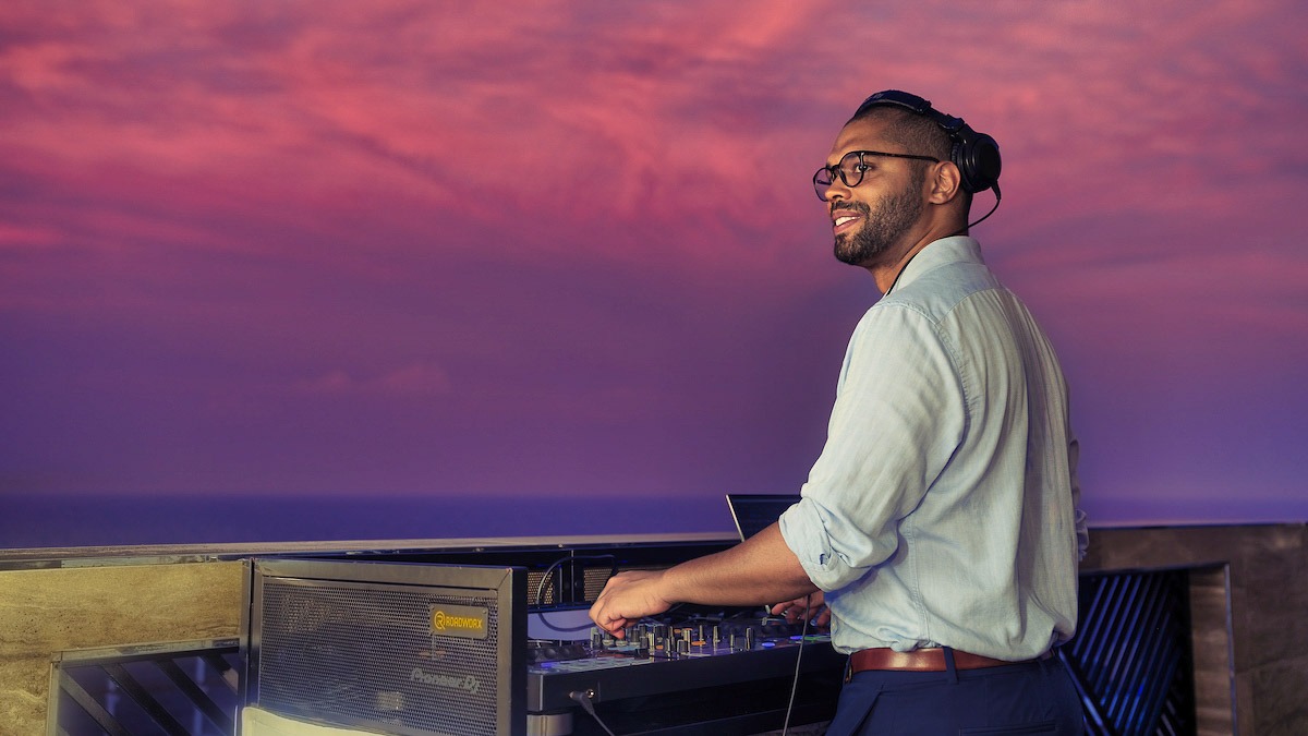 DJ plays on deck of cruise ship against a dramatic sky