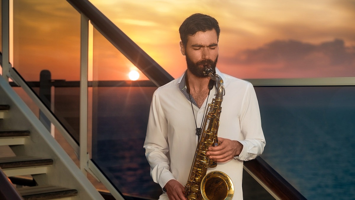 Sax player on deck of cruise ship with sun setting behind him