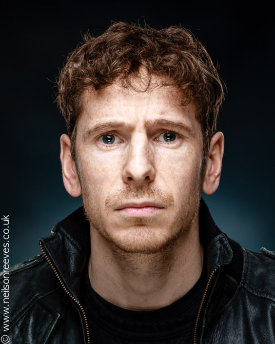 headshot featuring actor Gerard Kearns wearing black leather jacket and short red curly hair
