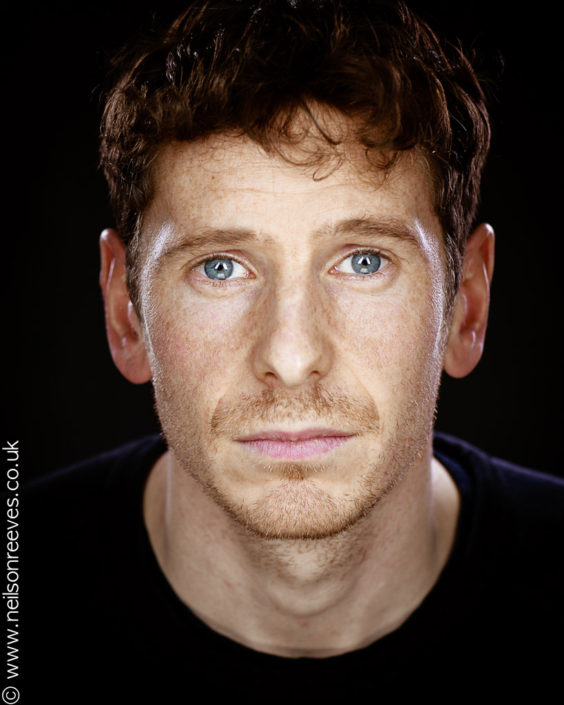 close crop actor headshot featuring actor Gerard kearns with freckles and stunning blue eyes plain background
