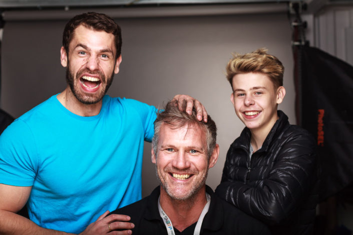 Behind scenes group shot features actor Kelvin Fletcher, Brayden Fletcher and Colin Boulter in the studio after a shoot. photographed against a black background with studio light in shot