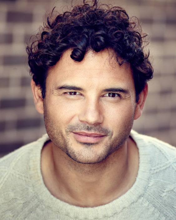 actor headshot featuring Ryan Thomas taken outside against brown brick wall