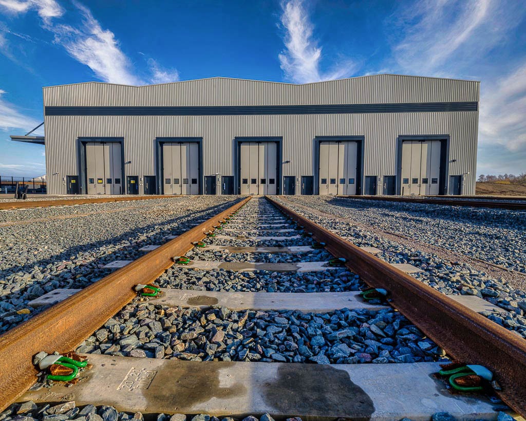 Siemens trains factor in tracks in foreground, leading to train hanger garage doors in background