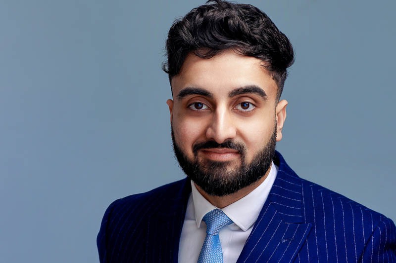 corporate headshot grey background indian man wearing pinstripe blue jacket 