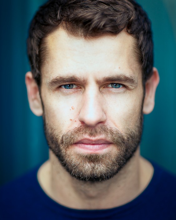 actor headshot portrait featuring Kelvin Fletcher against blue background
